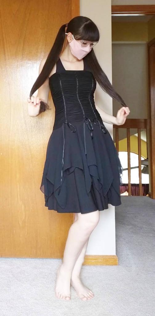 A young woman with pigtails models a black kawaii dress.